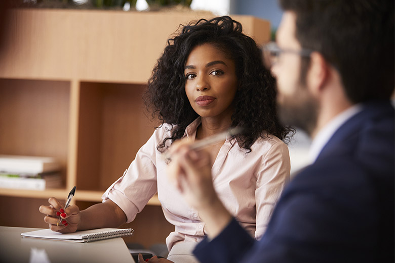 Businesswoman Making Notes Sitting At Table Meeting With Colleagues In Modern Office